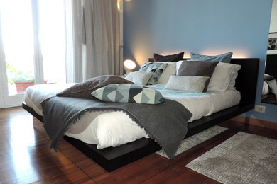 This is an example of a small modern master bedroom in Turin with blue walls, dark hardwood flooring and brown floors.