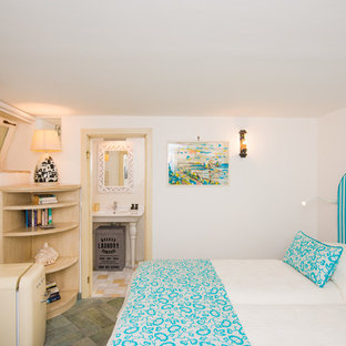 Modelo de dormitorio principal, costero, pequeño, con paredes blancas y suelo de ladrillo