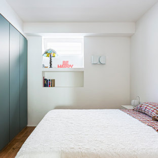 Foto de dormitorio principal, minimalista, grande, con paredes blancas, suelo de madera en tonos medios y suelo marrón