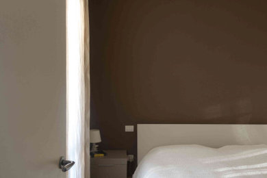 Modelo de dormitorio principal moderno de tamaño medio con paredes marrones