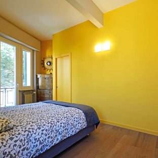 Foto de dormitorio principal, minimalista, con paredes amarillas y suelo laminado