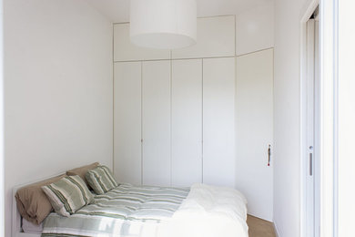 Foto de dormitorio contemporáneo pequeño con paredes blancas, suelo de madera clara y suelo marrón