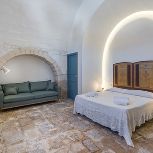 Esempio di una grande camera matrimoniale mediterranea con pareti bianche, pavimento in pietra calcarea e pavimento beige