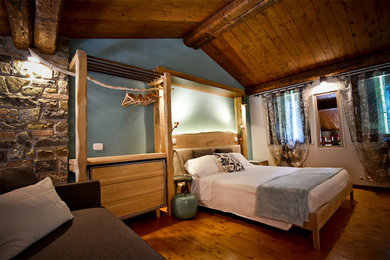 他の地域にある広いカントリー風のおしゃれなロフト寝室 (青い壁、無垢フローリング、ベージュの床) のインテリア