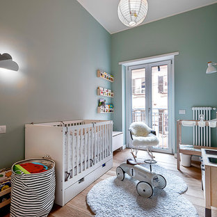 Esempio di una cameretta per bambini da 1 a 3 anni scandinava con pareti verdi e pavimento in legno massello medio