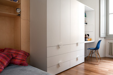 Modelo de dormitorio infantil actual con paredes blancas, suelo de madera en tonos medios y suelo marrón