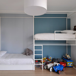 Idee per una cameretta per bambini da 4 a 10 anni minimal con pareti blu, pavimento in legno massello medio e pavimento marrone