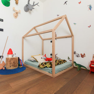 Foto di una cameretta per bambini da 1 a 3 anni mediterranea con pareti bianche, pavimento in legno massello medio e pavimento marrone
