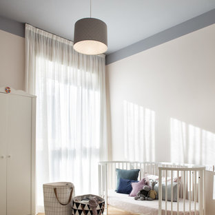 Esempio di una cameretta per neonati neutra scandinava con pareti bianche, parquet chiaro e pavimento beige