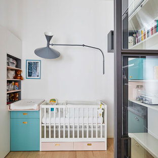 Ispirazione per una cameretta per neonati neutra minimal di medie dimensioni con pareti bianche, parquet chiaro e pavimento beige