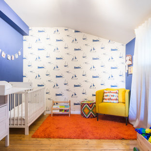 Immagine di una grande cameretta per neonati contemporanea con pareti blu, pavimento in legno massello medio e pavimento marrone