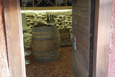 Exemple d'une cave à vin nature de taille moyenne avec tomettes au sol, des casiers losange et un sol rouge.