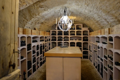 Cette photo montre une grande cave à vin chic avec des casiers et un sol gris.
