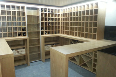 Aménagement d'une grande cave à vin contemporaine avec tomettes au sol et un présentoir.