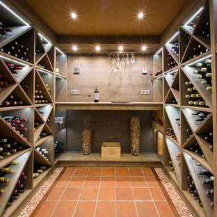 Idée de décoration pour une grand cave à vin design avec un sol en carreau de terre cuite et des casiers losange.
