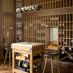 Idée de décoration pour une grand cave à vin design avec un sol en bois brun et des casiers.