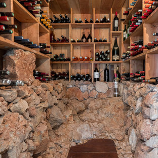 Inspiration pour une cave à vin méditerranéenne avec un sol en bois foncé, des casiers et un sol marron.