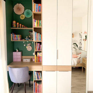 Esempio di una cameretta per bambini da 4 a 10 anni moderna di medie dimensioni con pareti verdi, pavimento in laminato, pavimento beige e carta da parati