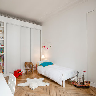 Idée de décoration pour une chambre d'enfant de 4 à 10 ans nordique de taille moyenne avec un mur blanc, un sol en bois clair et un sol beige.