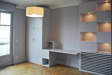 Ejemplo de habitación infantil unisex de 4 a 10 años contemporánea con escritorio, suelo de madera clara y paredes grises
