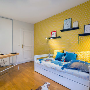 Réalisation d'une chambre d'enfant design avec un mur jaune, un sol en bois brun et un sol marron.