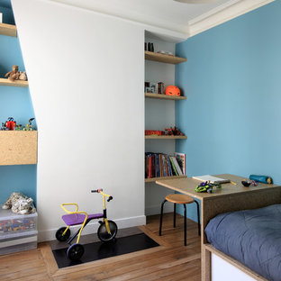Idée de décoration pour une chambre de garçon de 4 à 10 ans design de taille moyenne avec un bureau, un mur bleu et un sol en bois brun.