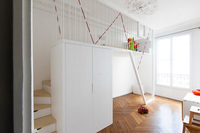 Modelo de habitación infantil unisex de 4 a 10 años actual pequeña con paredes blancas y suelo de madera en tonos medios