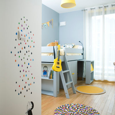 Example of a mid-sized trendy gender-neutral light wood floor kids' room design in Paris with blue walls