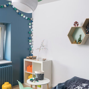 Idée de décoration pour une chambre de garçon de 4 à 10 ans design de taille moyenne avec un sol en bois clair, un sol beige et un mur blanc.