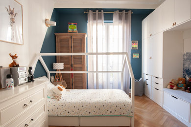 Idées déco pour une chambre d'enfant de 1 à 3 ans moderne de taille moyenne avec un mur bleu, parquet clair et un sol beige.