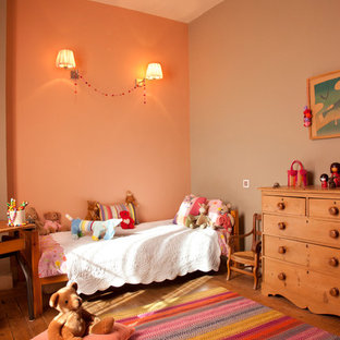 Aménagement d'une grand chambre d'enfant de 4 à 10 ans classique avec un sol en bois brun et un mur multicolore.