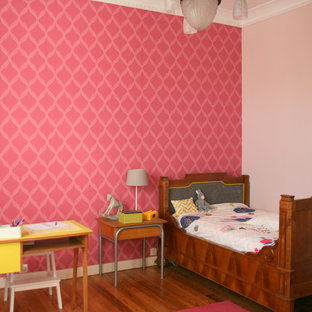 Idée de décoration pour une chambre d'enfant de 4 à 10 ans tradition de taille moyenne avec un mur rose et un sol en bois brun.