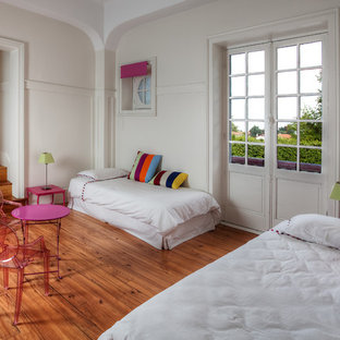 Idée de décoration pour une chambre d'enfant de 4 à 10 ans bohème avec un mur blanc et un sol en bois brun.