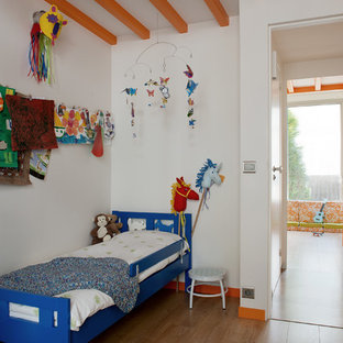 Réalisation d'une chambre d'enfant de 4 à 10 ans nordique de taille moyenne avec un mur blanc et un sol en bois brun.