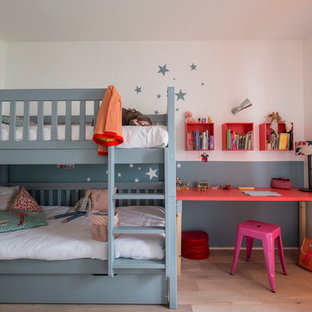 Cette image montre une chambre de fille de 4 à 10 ans design de taille moyenne avec un bureau, un sol en bois clair et un mur multicolore.