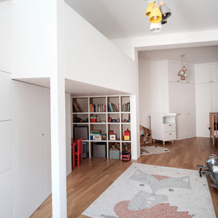 Réalisation d'une chambre d'enfant design avec un mur blanc, un sol en bois brun et un sol marron.