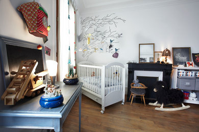 Photo of a medium sized contemporary gender neutral toddler’s room in Paris with beige walls, dark hardwood flooring and brown floors.