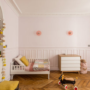 Cette image montre une chambre d'enfant design avec un mur rose et un sol en bois brun.