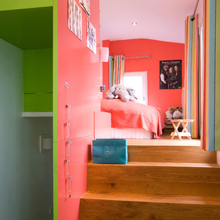 Cette photo montre une grand chambre d'enfant de 4 à 10 ans tendance avec un mur rose et un sol en bois brun.