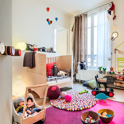 Mid-sized trendy gender-neutral medium tone wood floor kids' room photo in Paris with white walls