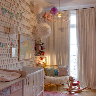 Imagen de habitación de bebé niña nórdica con paredes multicolor, suelo de madera clara y suelo beige