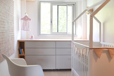 Réalisation d'une chambre de bébé style shabby chic avec un mur rose et parquet clair.