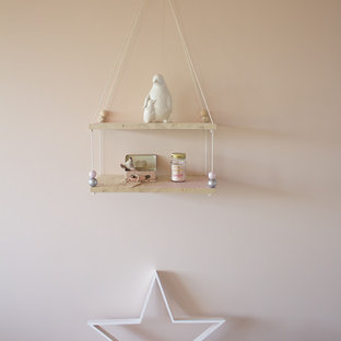 Esempio di una cameretta per neonata shabby-chic style di medie dimensioni con pareti rosa, pavimento in laminato e pavimento grigio