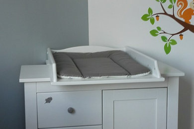 Idée de décoration pour une petite chambre de bébé fille design avec un mur gris, sol en stratifié et un sol gris.