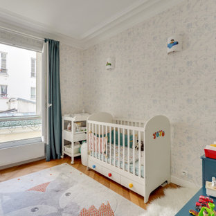 Idée de décoration pour une petit chambre de bébé garçon design avec un mur multicolore, un sol en bois brun, un sol marron et du papier peint.