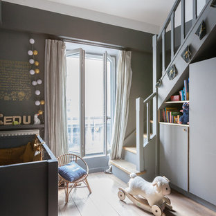 Exemple d'une chambre de bébé neutre tendance de taille moyenne avec un mur gris, un sol en bois clair et un sol beige.