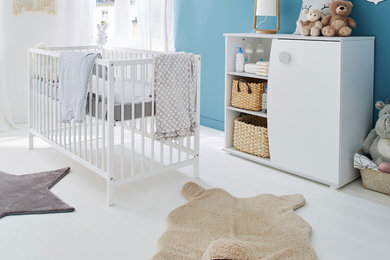 Cette image montre une chambre de bébé neutre nordique avec un mur bleu.