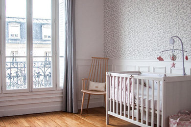 Cette image montre une chambre de bébé fille nordique avec un mur blanc, parquet foncé et un sol marron.