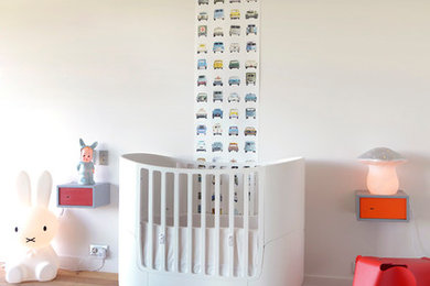 Idée de décoration pour une chambre de bébé neutre minimaliste de taille moyenne avec un mur blanc et un sol en bois brun.