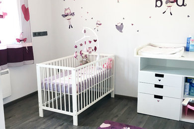 Idées déco pour une chambre de bébé fille de taille moyenne avec un mur gris, sol en stratifié et un sol marron.